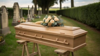 Cercueil en chêne clair couvert de roses crème dans un cimetière fleuri