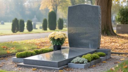 Tombe en granit gris couverte de mousse verte sur la semelle, chrysanthèmes crème